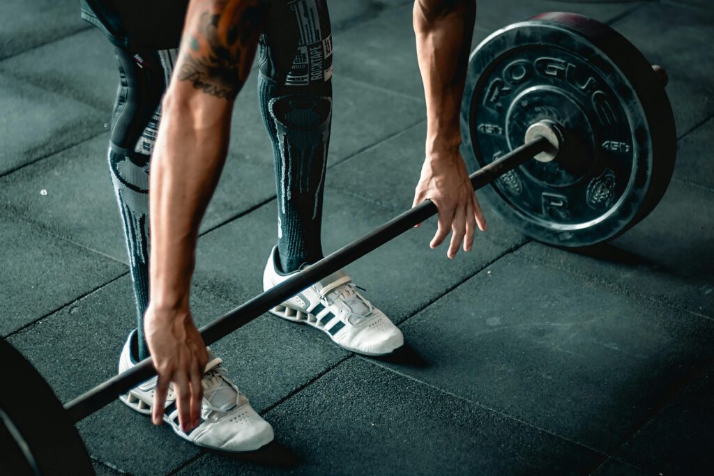 A man preparing his grip on a barbell for deadlift.