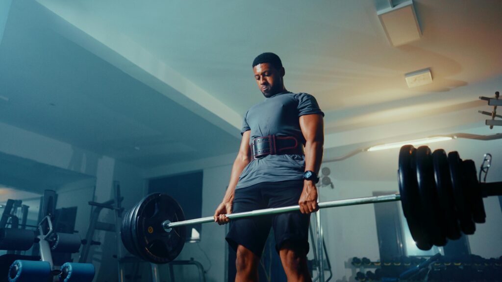 A man wearing a lifting belt performing a deadlift.