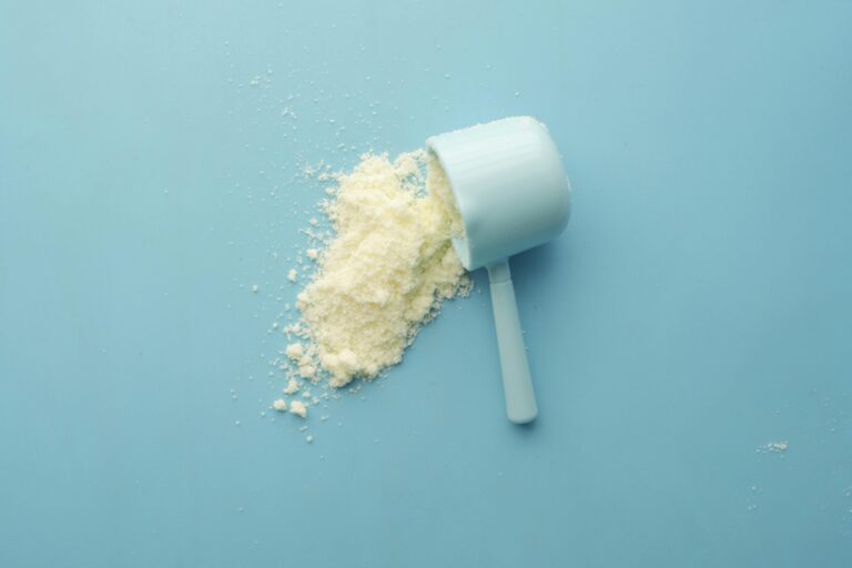 A scoop of whey protein spilled on a table.