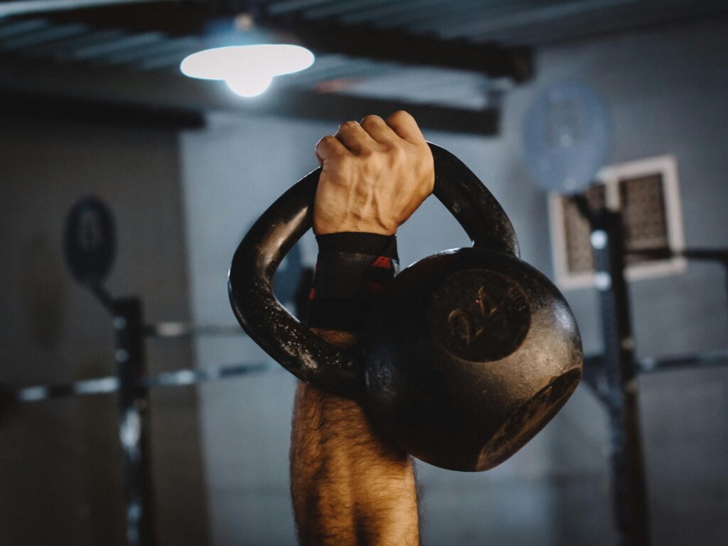 Man lifting a kettlebell while wearing wrist wraps.