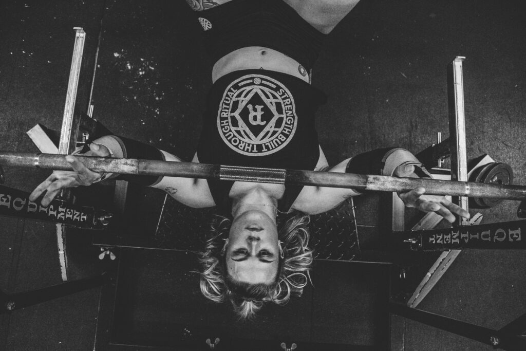 Woman bench pressing alone on a bench with built-in safety bars