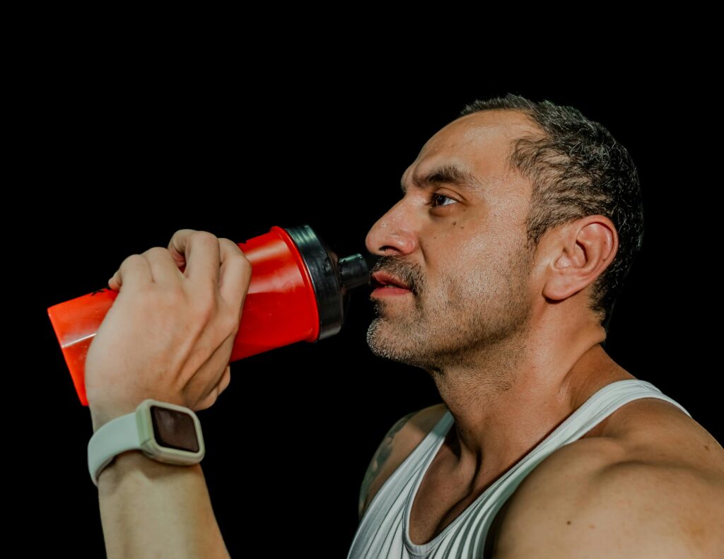 Man drinking from a shaker bottle in the gym