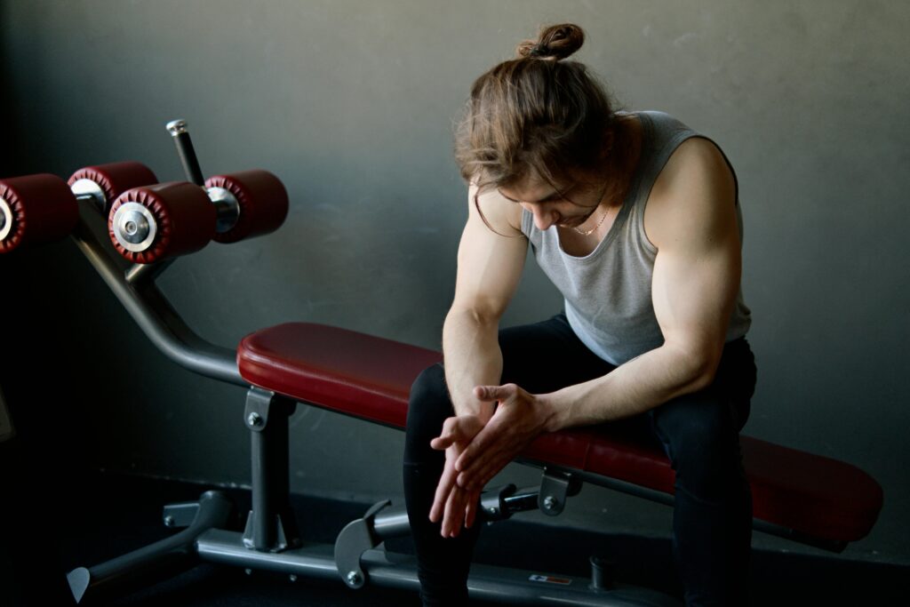 When to deload: lifter sitting on a gym bench during a rest period