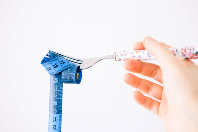 Fork with a measuring tape representing a calorie deficit